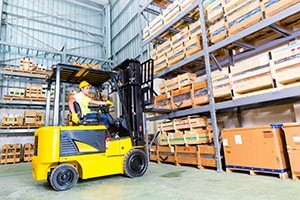 A guy using a fork lift in a warehouse